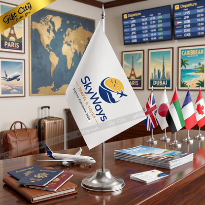 A tabletop scene showing a small white desk flag with the Skyways logo on a silver stand, surrounded by travel-themed props including passports, a suitcase, a model airplane, brochures, and other national flags. A yellow 'Gift City' banner appears in the top-left corner.