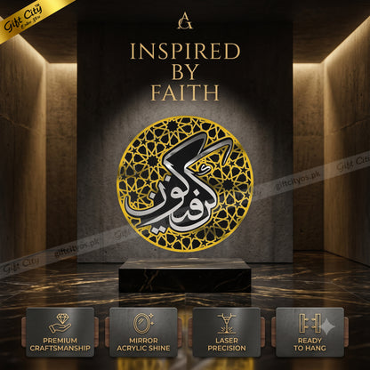 A large acrylic mirror wall art piece featuring Arabic calligraphy in black and white over a gold geometric pattern, displayed on a black marble pedestal in a modern gallery setting with warm lighting. Four feature badges at the bottom highlight premium craftsmanship, mirror acrylic shine, laser precision, and readiness to hang.